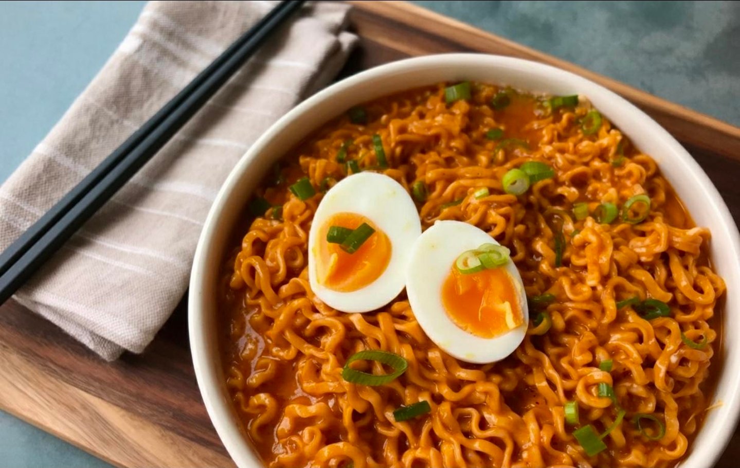 Delicious bowl of Buldak ramen garnished with soft-boiled eggs and green onions